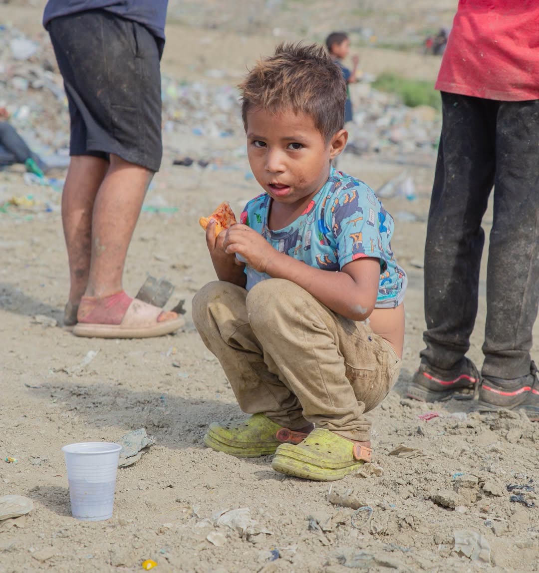 A young boy pausing for a meal in a hard place